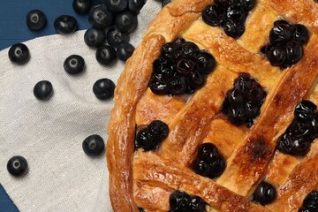 Tasty homemade pie with blueberries on blue table, flat lay