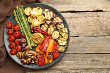 Delicious grilled vegetables on wooden table, top view. Space for text