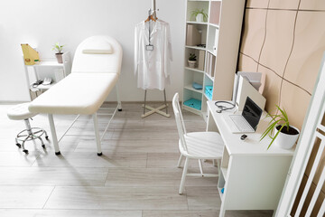 Interior of medical office with couch, shelf units and doctor's workplace