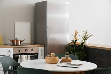 Stylish interior of modern kitchen with fridge, counter and dining table