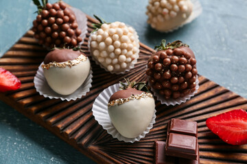 Wooden board with chocolate covered strawberries on dark background