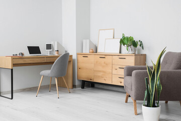 Interior of home office with laptop, tablet computer and headphones on wooden desk