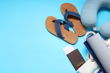 Travel pillow, ticket, wallet, map, bag and flip-flops on blue background