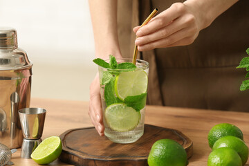 Young woman with glass of fresh mojito at home, closeup
