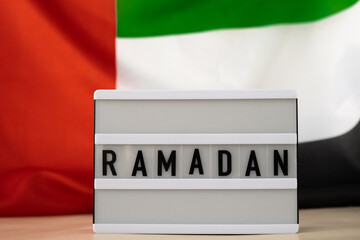 RAMADAN text frame on United Arab Emirates waving flag made from silk material. Public holiday celebration background. Commemoration Day Muslim The National Flag of UAE. Patriotism Blessed Holy Month