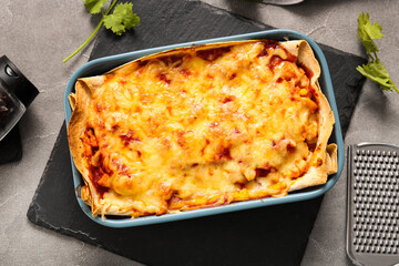Baking dish with tasty enchilada on grunge background