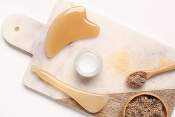 Beautiful composition with tray, facial massage tools and sea salt on marble background, closeup