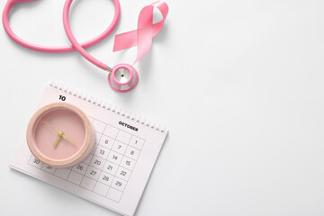 Fototapeta premium Pink ribbon, alarm clock, calendar and stethoscope on light background. Breast cancer awareness concept
