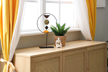 Stylish decor on commode near window with curtains in living room
