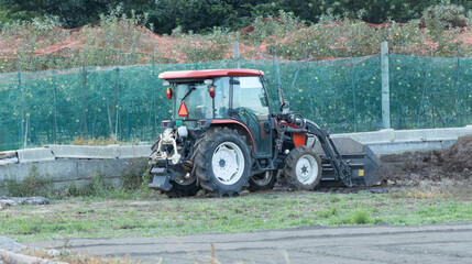 Fototapeta premium Tractor Operating in a Japanese Orchard, Emphasizing the Role of Mechanized Farming Equipment in Maintaining and Protecting Fruit Crops, with Apple Trees Visible in the Background