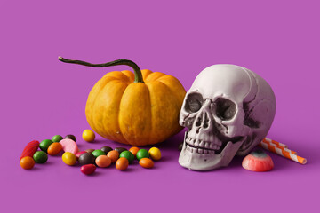 Human skull, pumpkin and candies for Halloween on purple background