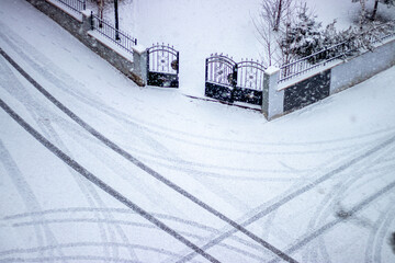 Naklejka premium Snowy road with tire tracks leading to a gate, symbolizing life's paths and new beginnings.