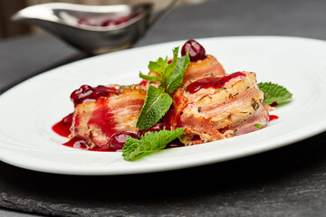 Gourmet bacon-wrapped chicken rolls with cherry sauce, garnished with mint, perfect for fine dining