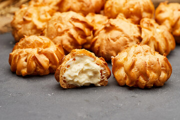 Delicious cream-filled profiteroles arranged on a dark slate surface, perfect for dessert lovers