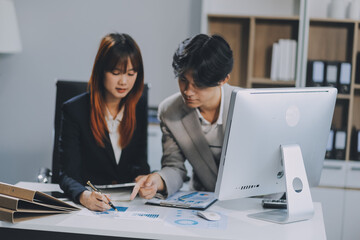 Entrepreneur Asian businessman and businesswoman discussing new business project in tablet in modern Meeting In Modern Office, Asian business casual concept.