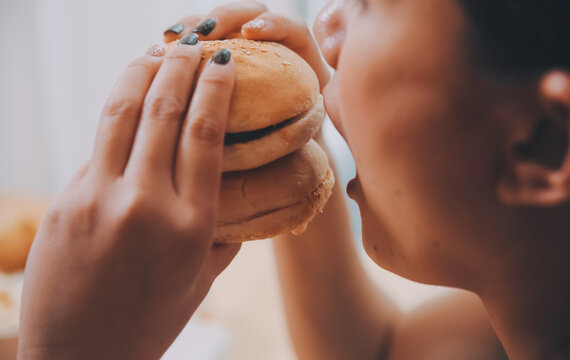 Binge eating disorder concept with woman eating fast food burger, fired chicken , donuts and desserts