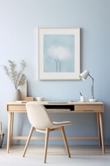 A light blue wall with a wooden desk with a white chair and a framed abstract flower painting, a white lamp, a mug, and a laptop.