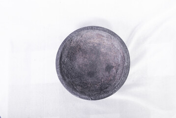 Against the grey floor, the stone mortar and pestle (cobek) stands out with its rustic charm. This traditional kitchen tool, carved from robust stone, is perfect for grinding spices and making pastes.