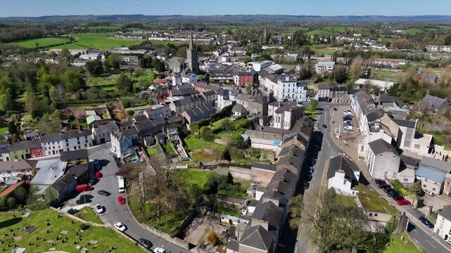 Clones Town, County Monaghan, Ireland, April 2023. Drone pushes forward over old buildings towards St Tiarnach's Church of Ireland overlooking the Diamond in the center of town.