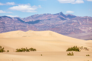 Sand dunes against the backdrop of mountains and sky in Death Valley, California