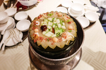 close up of Chinese winter melon soup with mushroom, pork, shrimp, cucumber in a silver pot