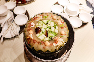 close up of Chinese winter melon soup with mushroom, pork, shrimp, cucumber in a silver pot