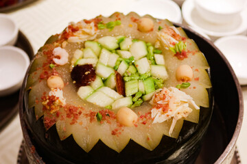 close up of Chinese winter melon soup with mushroom, pork, shrimp, cucumber in a silver pot