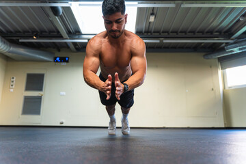 Latin man doing push-ups with clapping during a workout