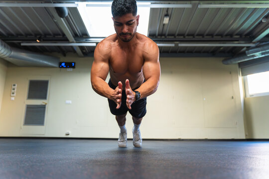 Latin man doing push-ups with clapping during a workout