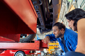 Professional technician man description to issue of car to customer woman before start repairing her car in car garage.