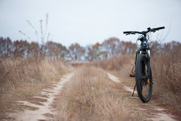 bike stands on in the field. A mountain bike stands on a field path with dry autumn grass. cycling. Mountain bike. outdoor cycling activities. active rest, sports, travel