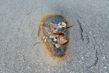 Asphalt road cracked and collapsed from above. Depression in asphalt surface caused by subgrade settlement. Asphalt dent, damaged asphalt road, cracking in older asphalt pavements.