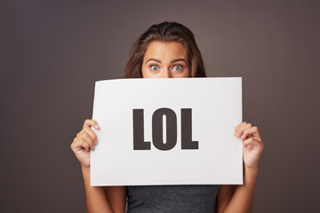 Laugh, comment and portrait of woman with card for social media review, lol and internet slang in studio. Funny, like and happy girl with sign for online language, culture or meme on grey background