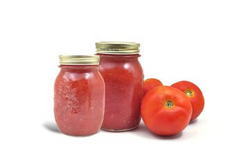 Photo of two glass jars filled with homemade tomato sauce sits alongside three fresh tomatoes, highlighting the sauce’s natural ingredients, isolated on white background.