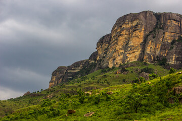 Naklejka premium Tall sandstone cliffs, against ominous dark clouds in Royal Natal National Park, in the Drakensberg mountains of South Africa. 