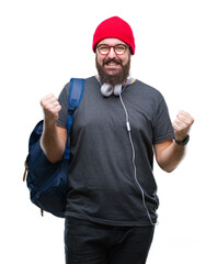Fototapeta premium Young hipster man wearing red wool cap and backpack over isolated background celebrating surprised and amazed for success with arms raised and open eyes. Winner concept.