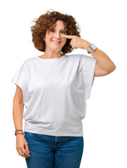 Beautiful middle ager senior woman wearing white t-shirt over isolated background Pointing with hand finger to face and nose, smiling cheerful