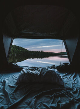 View from inside a tent looking out at peaceful lake at sunset