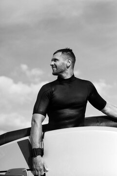 A man athlete comes out of the water with wingfoil equipment.