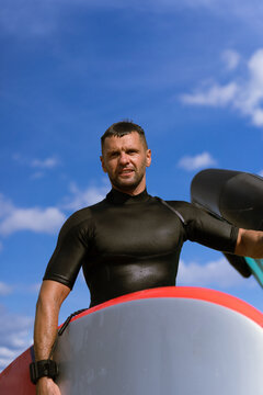 A man athlete comes out of the water with wingfoil equipment.