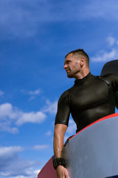 A man athlete comes out of the water with wingfoil equipment.