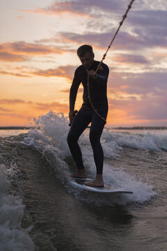Low angle view of man wake surfing in lake against sunset sky