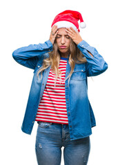 Beautiful young blonde woman wearing christmas hat over isolated background suffering from headache desperate and stressed because pain and migraine. Hands on head.