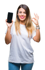 Fototapeta premium Young beautiful woman showing blank screen of smartphone over isolated background doing ok sign with fingers, excellent symbol