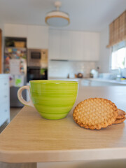 Taza de café y galletas encima de mesa de cocina.