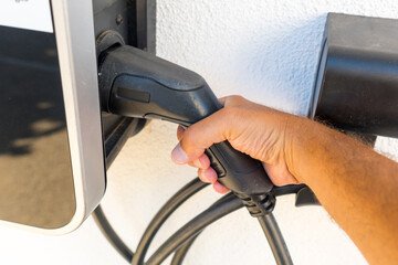A person is plugging in a car to a charging station