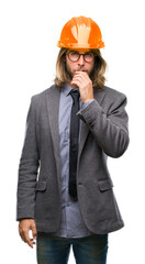 Young handsome architec man with long hair wearing safety helmet over isolated background looking confident at the camera with smile with crossed arms and hand raised on chin. Thinking positive.