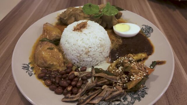 Asian food Nasi Lemak is a rice dish infused with coconut milk. Served with sambal, curry chicken, fried peanut, boiled egg and fried anchovies.