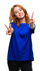 Young beautiful woman over isolated background smiling looking to the camera showing fingers doing victory sign. Number two.