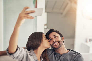 Selfie, happy and couple on sofa kiss for social media, online post and profile picture in living room. Dating, love and people hug, embrace and take photo for bonding, relationship and relax in home